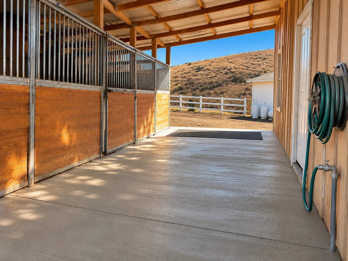 After: new broom-finished concrete barn aisle with saw-cut joints beside the horse stalls